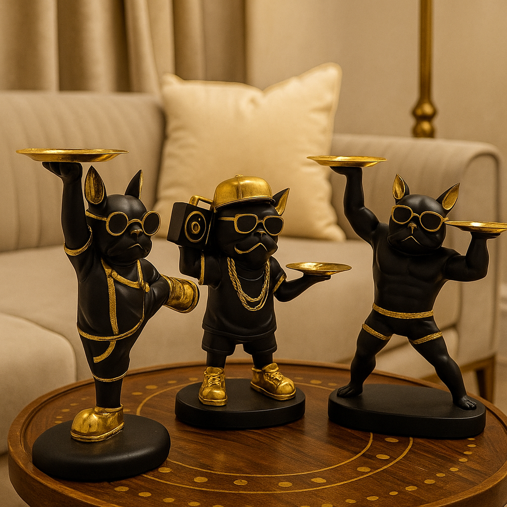 Three decorative statues of dogs in stylish outfits on a wooden table.
