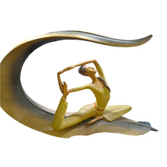 Gold sculpture of a figure on a crescent moon held by a person in a store setting.