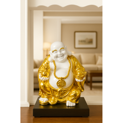 Gold and white Buddha statue on a black base in a room with a couch and lamp.